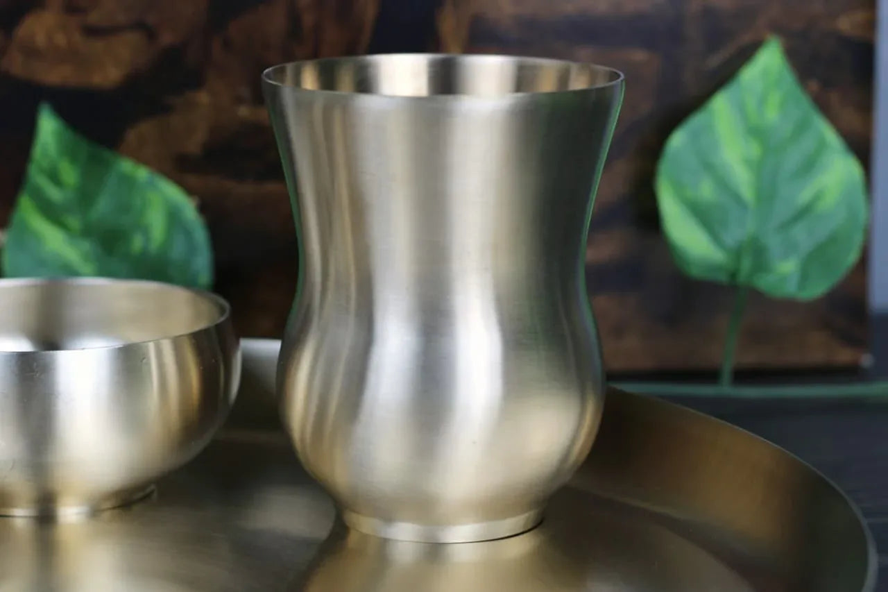 Six-piece Kansyakar bronze dinner set with curvy design and matte finish, featuring pure bronze material and glassware.