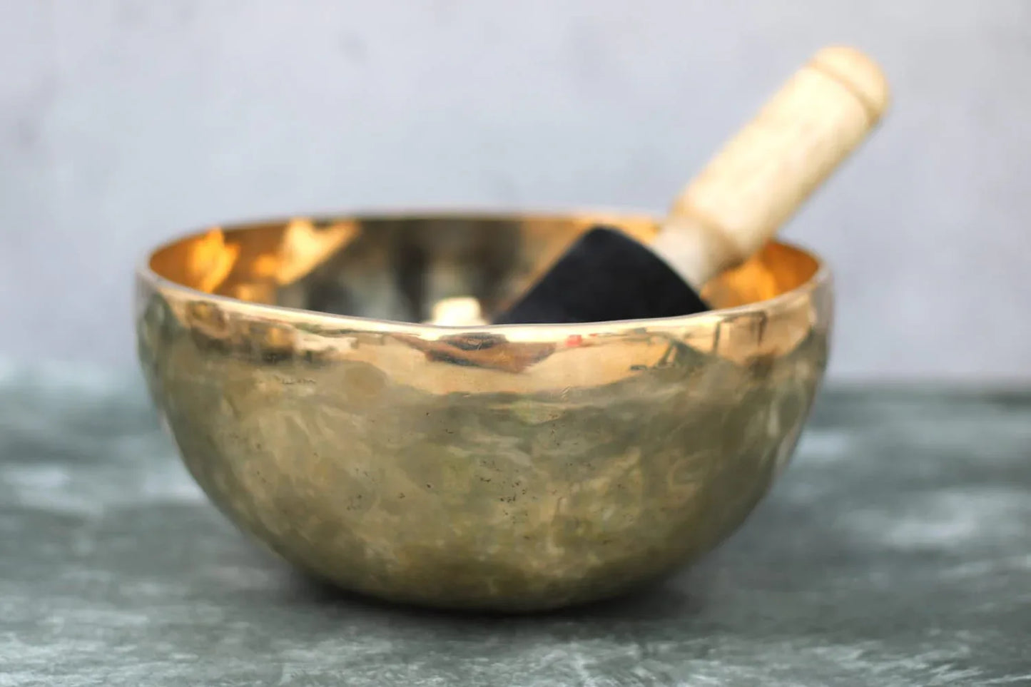 Handcrafted bronze Kansa singing bowl with wooden mallet, used for meditation and sound healing, available in two sizes by Kansyakar.